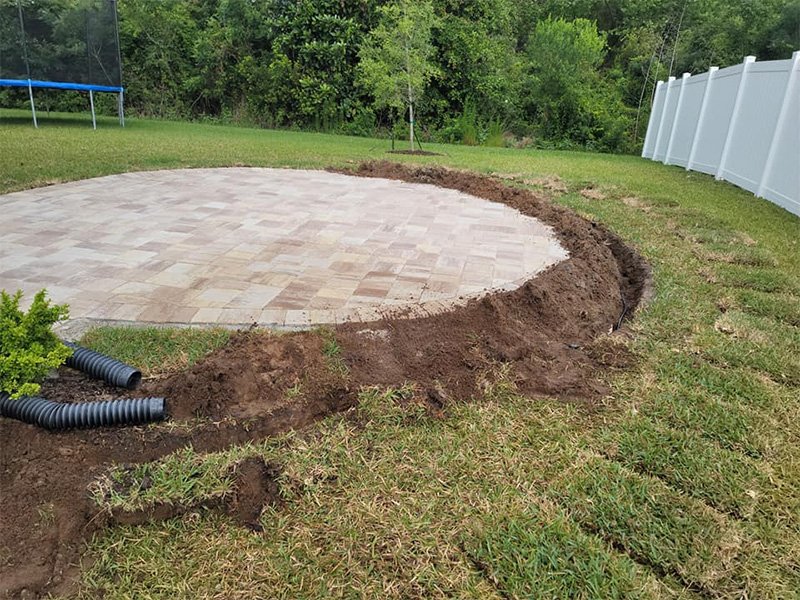 Custom drainage solution installed around a circular paver patio.